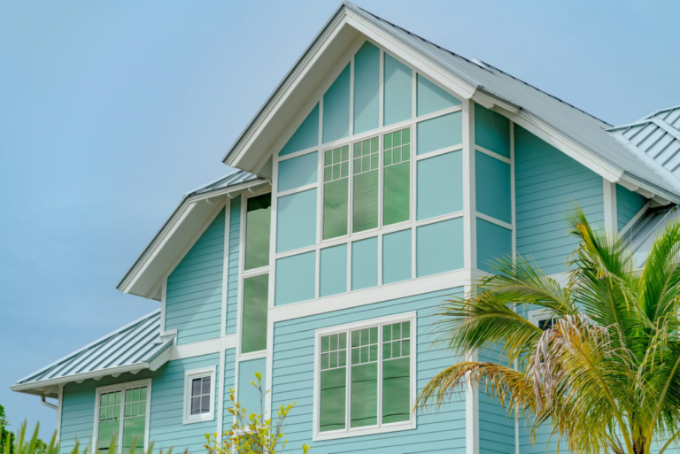 An image of a man painting a house freshly painted light blue